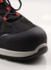 Preview: The image shows the front of a black shoe with a soft, rounded toe area. Red laces thread through the upper, which is made of a durable fabric.