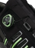 Preview: The image shows a part of a sporty shoe in black with green accents. A round closure mechanism is prominent to adjust the lacing. There are also side slits.