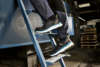 Preview: The image shows a person climbing a blue ladder with special work shoes. The shoes are sporty and provide good grip, and the background appears industrial.