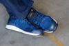 Preview: The image shows a foot in a blue, sporty shoe with a light sole. The shoe has a modern design and laces, and the person is wearing dark pants.