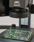 Preview: The image displays a green circuit board under a microscope, labeled "4K Makrolite". The board features various electronic components and is placed on a table.