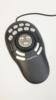 Preview: The image shows an oval, black controller with a central round dial and several buttons. The controller has a wired connection and is intended for multimedia applications.