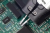 Preview: The image shows a green circuit board with electronic components. Two pliers precisely grip a spot on the board. Detailed circuits are visible.