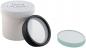 Preview: The image shows a round, black lens lying in a white container. Next to it is a flat, transparent lens in a light shade.