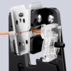 Preview: The image shows a crimping tool holding an orange wire in a holder. The tool has metallic parts with holes and a transparent plastic component for guiding the wire.