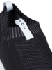 Preview: The image shows a black shoe in close-up style. It features a knit-like surface with an elastic collar and a white pull tab at the back.