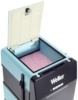 Preview: The image shows a simple black box with a light blue lid that is open. Inside, a pink, fluffy surface is visible. On the front are the letters "Weller" and some control buttons.