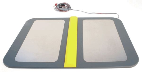 The image shows a rectangular mat with two smooth, light surfaces and a central yellow line. At one end, there is a cable that leads to the power source.