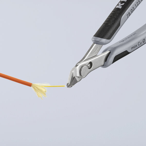 The image shows a pair of pliers gripping a fine, orange wire. The wire has a fan-shaped, yellow structure at the end. The background is neutral and bright.