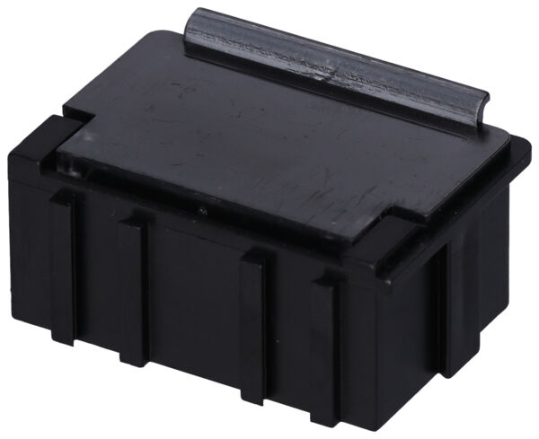 The image shows a small, rectangular box made of black plastic. It has a smooth top and vertical grooves on the sides. The lid is flat with a small raised area.