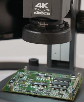 The image displays a green circuit board under a microscope, labeled "4K Makrolite". The board features various electronic components and is placed on a table.