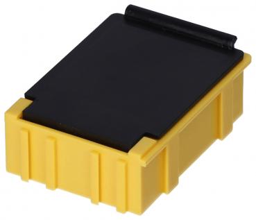 The image shows a small, rectangular container. It has a yellow bottom with grooves and a black lid. The lid is flat and has a slight overhang.