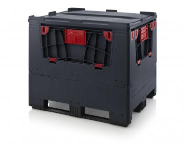 The image shows a large, square box made of dark plastic. It has red highlighted sides and a sturdy, coarse surface. The box is placed on pallets and appears robust.