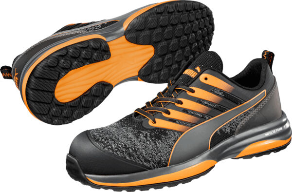 The image shows a pair of sports or casual shoes. They are black with gray and orange accents. The sole has a non-slip tread and the shoes appear modern and sporty.