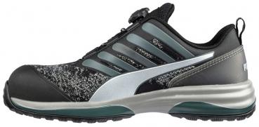 The shoe is dark gray with silver and green accents. It has a padded sole, a non-slip outsole, and a simple, sporty cut.