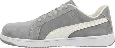 The image shows a gray sports shoe made of soft material. It has a white sole, a white stripe on the side, and laces. The shape is modern and casual.