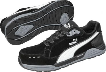 The image shows black sports shoes with gray and white details. The sole is sturdy with a non-slip pattern. They have laces and the brand "Puma" is prominently visible.