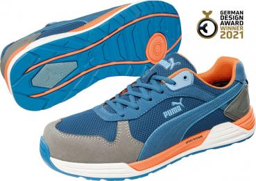 Das Bild zeigt einen sportlichen Schuh von Puma. Er hat ein blaues Obermaterial mit grauen und orangenen Akzenten. Die Sohle ist griffig und zeigt ein modernes Design.