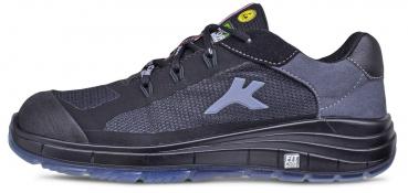 The shoe is a black, sporty half-shoe with an ankle-high design. It has a textured surface made of mesh and leather, as well as a grippy rubber sole. A logo is visible on the side.