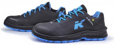 The image shows a pair of athletic shoes in black with blue shoelaces. On the side, there is a large, light blue "K" displayed. The sole is also designed in blue.