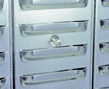 The image shows a series of silver compartments with handles. In the center of one of the compartments, there is a round locking mechanism that secures the compartment.