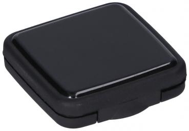 The image shows a small, square, black container with a smooth surface. It has rounded corners and a flap used for opening and closing.