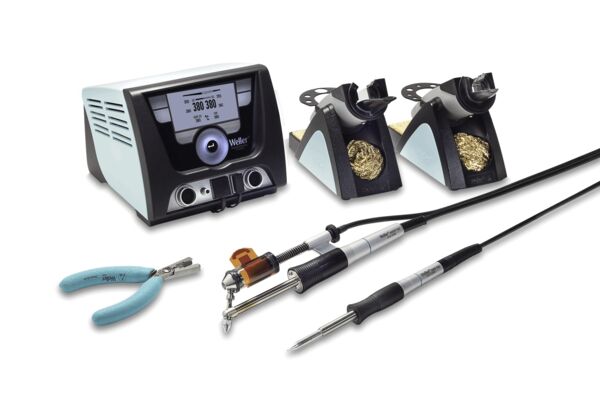 The image shows an electric soldering device with a screen, two soldering iron holders, a soldering iron, a pair of pliers, and various cables. The tools are designed for precise work.