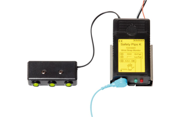 The image shows a security device with a black casing and a yellow label. It has a cable connection to a control box with three buttons that light up green.