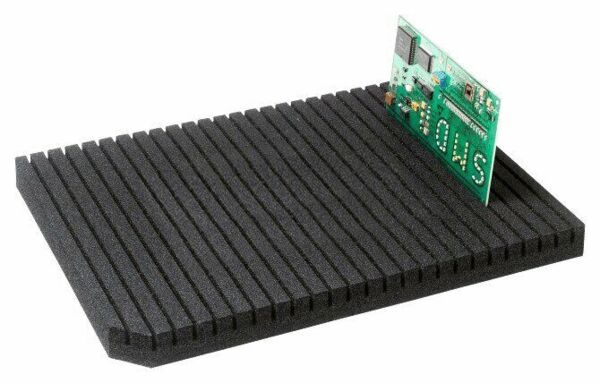 The image displays a rectangular, black foam pad with many parallel grooves. On the left side, there is a small green circuit board protruding from the foam.