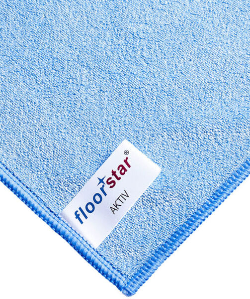 The image displays a light blue microfiber cloth with a textured surface. In one corner, the label "floorstar AKTV" is visible, bordered by a blue seam.