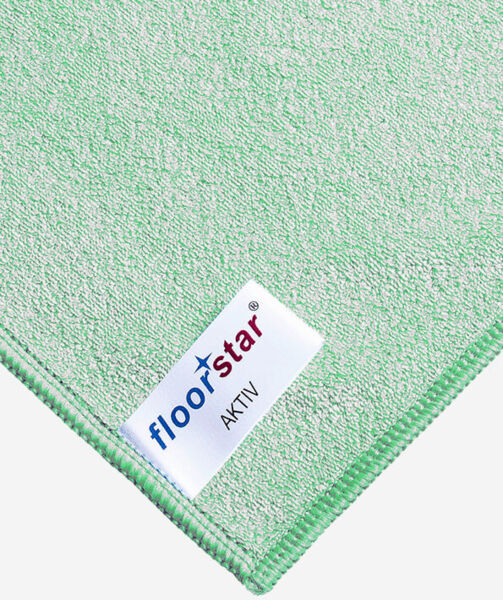 The image displays a section of a green cleaning cloth with a label. The label reads "floorstar" and "AKTIV". The edges are neatly sewn. The surface appears soft and absorbent.