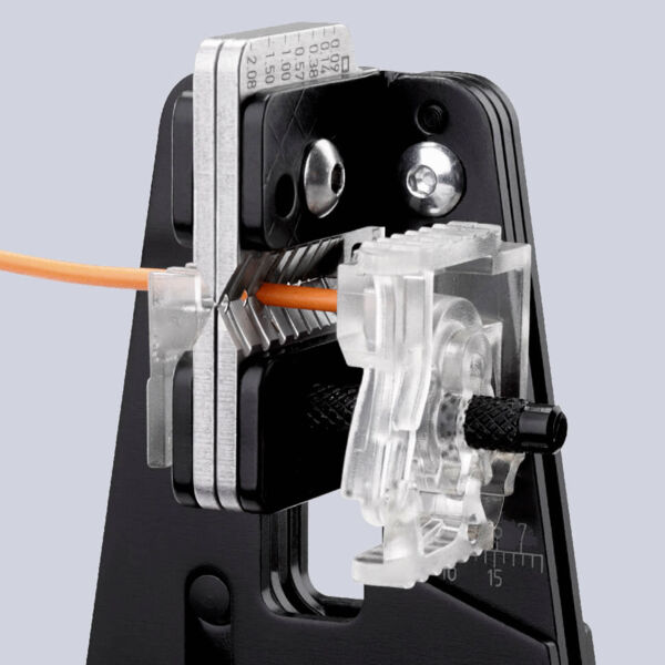 The image displays a tool for crimping cables. It features movable parts, an orange cord, and a transparent holder that secures the connection.