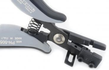 The image shows a special tool pliers with gray and black handles. It has a central spring and an opening for gripping or cutting materials.