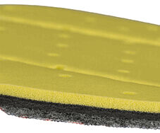 The image shows a multi-layered sponge. The top layer is yellow and soft, followed by a gray and then a black layer beneath it. The surface has small holes.