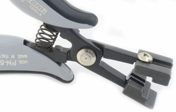 The image shows a black-gray pliers with a spring on the handle. It has a part that looks like a blade, and an opening for holding or cutting cables or wires.