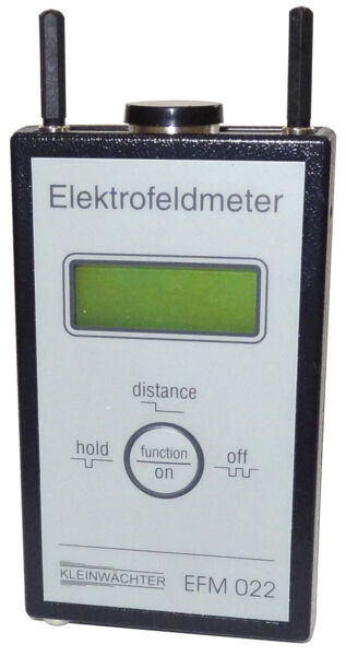 Das Bild zeigt ein digitales Elektrofeldmeter. Es hat eine rechteckige Form, eine graue Vorderseite mit einem großen Display in der Mitte, sowie zwei Antennen oben. Tasten sind darunter angeordnet.