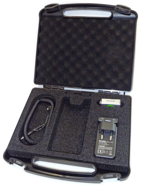 The image shows an open, black suitcase with foam inserts. Inside the suitcase, there is a charger, a spiral cable, and a free space for another device.