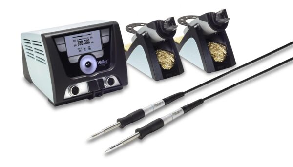 The image shows a soldering station with a control unit that has a display, as well as two soldering irons with individual holders. The holders contain solder or cleaning material.