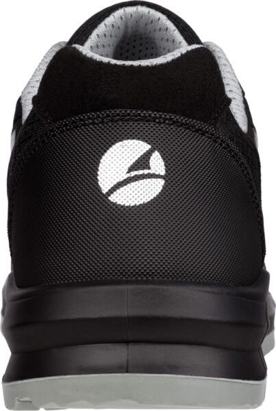 The image shows the rear view of a black sports shoe. The sole is gray and slightly elevated. On the back part, a white logo is visible, oval-shaped with a curved line.