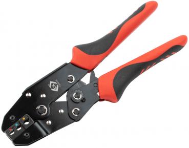 The image shows a cable cutter with red rubber grips. It has a black metal plate with several openings and a mechanism for wire twisting. The grips are ergonomically shaped.