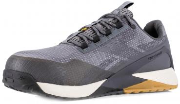 The shoe is a sporty training shoe in shades of gray. It has a breathable, textured upper, flat laces, and a sturdy, grippy sole. The heel is slightly elevated.