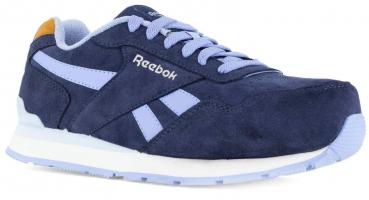 The shoe is a low-cut sneaker in dark blue suede. It features light, lilac accents and a white rubber sole. The logo "Reebok" is visible on the shoe.