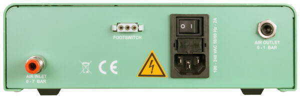 The image shows the back of a green device. There are sockets for air intake and exhaust, a foot switch connection, and a power connection with a switch. A warning symbol is visible.