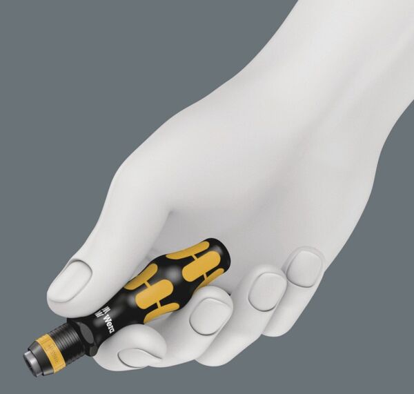 A white hand holds a black screwdriver with yellow accents. The background is gray. The hand has a natural shape and the fingers are slightly bent.