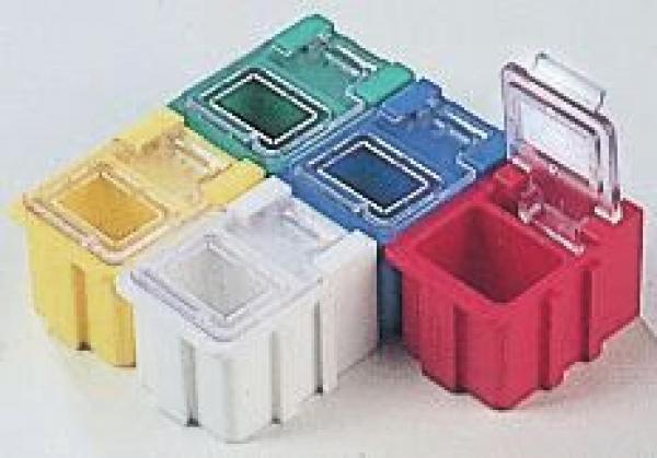 The image shows five small, square plastic boxes in various colors: Yellow, Green, Blue, White, and Red. Some have transparent lids. They are stackable and have rounded edges.