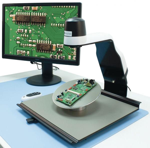 In the image, a microscope is positioned over a circuit board. The circuit board is placed on a rotating plate, and a screen displays an enlarged view of the board.