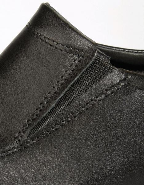 The image shows part of a black leather shoe. The shoe has elastic inserts and fine stitching that give it an elegant appearance.