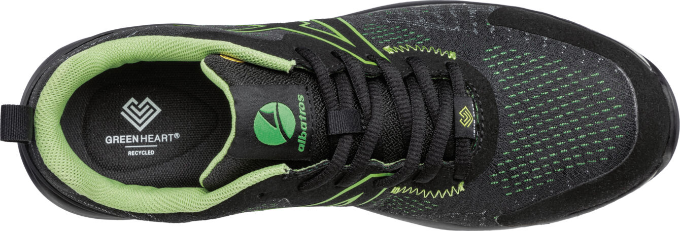 The image displays a sporty shoe made from black material with green accents. It features a breathable surface, laces, and a reinforced toe box. The insole reads "GREENHEART".