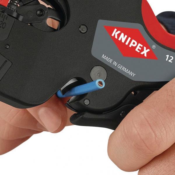 Das Bild zeigt eine Hand, die ein Kabelentblatter-Werkzeug von Knipex hält. Es hat eine schwarze Oberfläche und einen roten Griff. Ein blauer Draht wird durch das Werkzeug geführt.