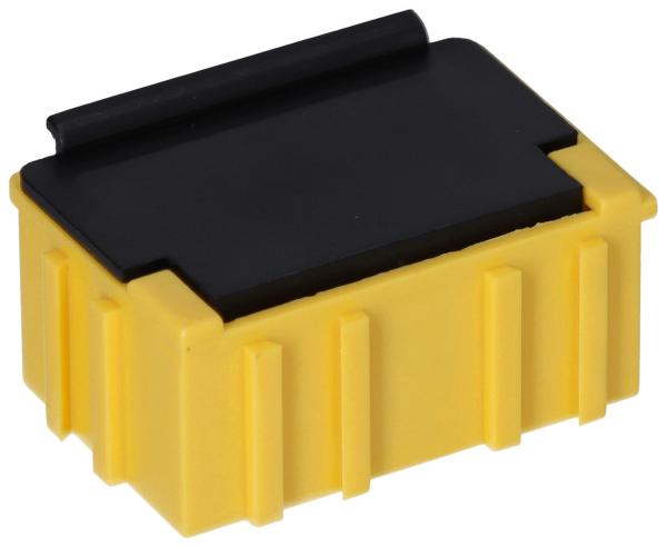 The image shows a rectangular, yellow plug or a box with a black cover on top. The sides are textured with vertical grooves. The shape is compact and sturdy.